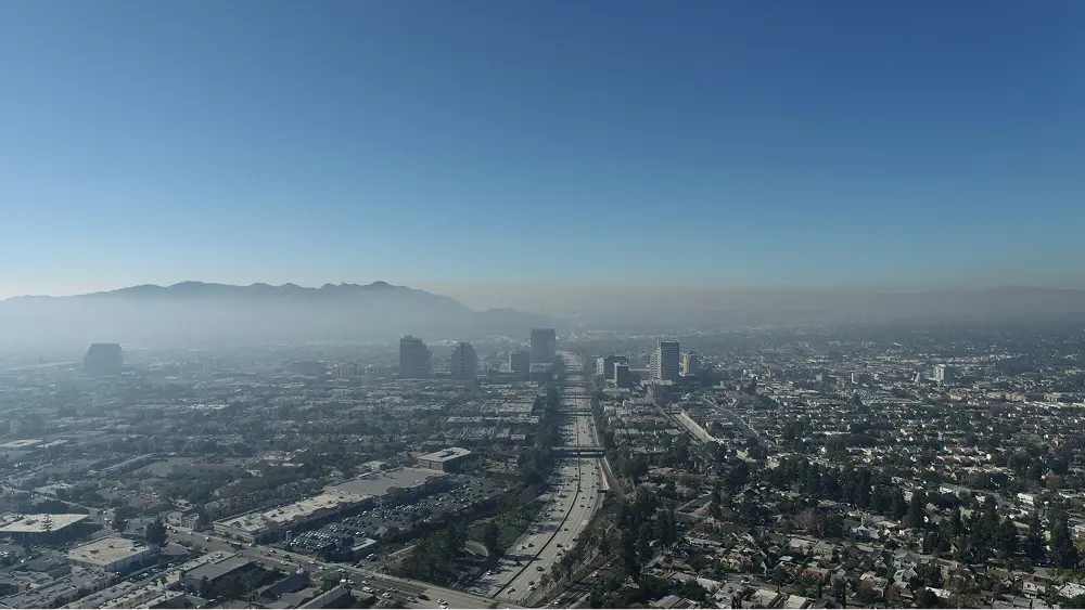 View of a California city with blue skies and a layer of fog, illustrating EPA-regulated air pollution conditions