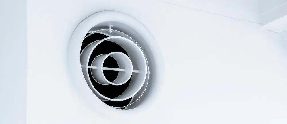 A white HVAC unit mounted on a clean white wall