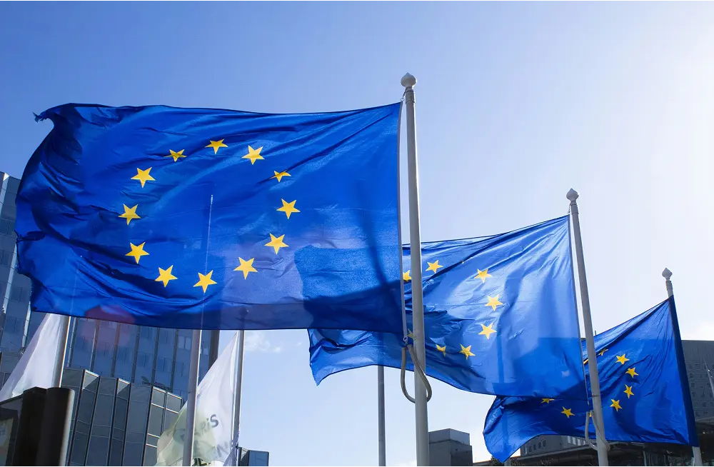 European Union flags waving in the wind against a clear blue sky symbolizing EU governance