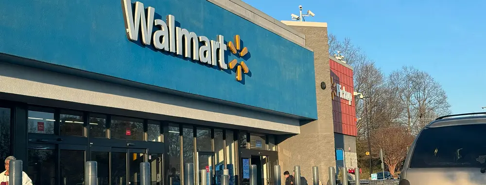 Front of a Walmart store with prominent signage main entrance and customers coming or going