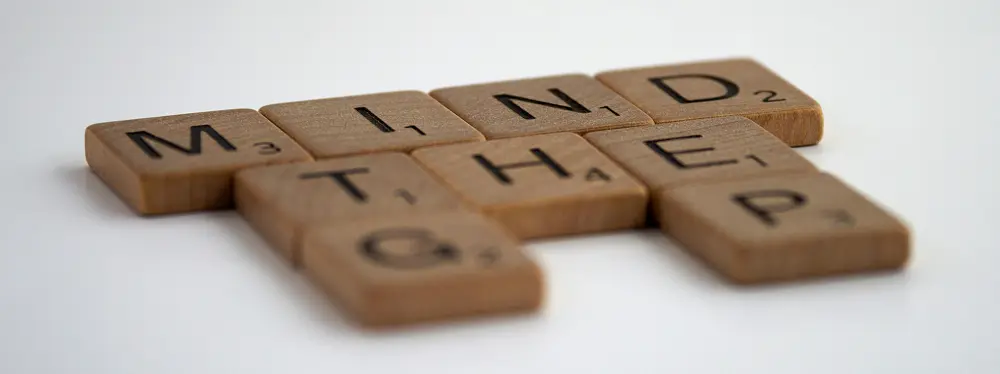 Scrabble tiles arranged to spell Mind the Gap on a white table