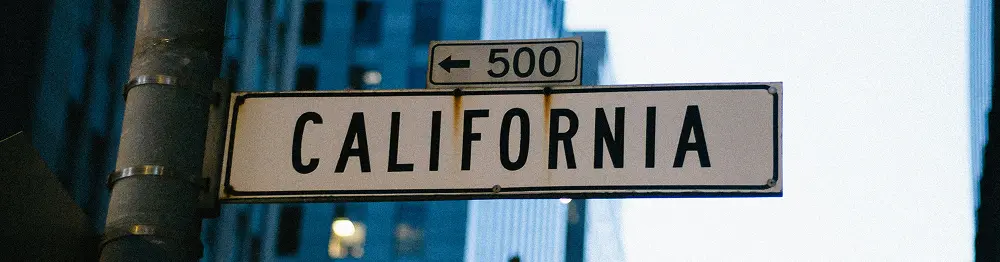 Street sign reading California mounted on a pole set against an urban background