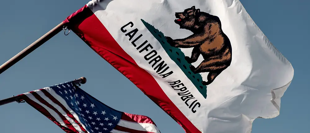 California state flag and United States flag flying against a clear blue sky