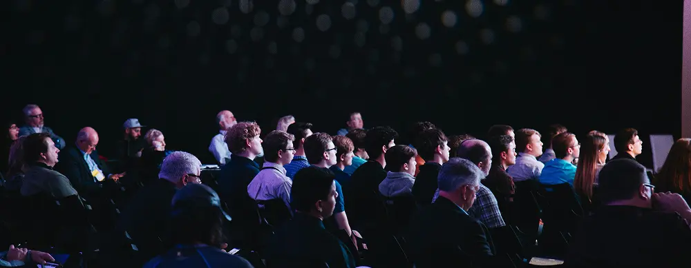 Large dimly lit conference room filled with people attending an event