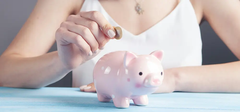 Woman putting a coin into a piggy bank, symbolizing budget and savings