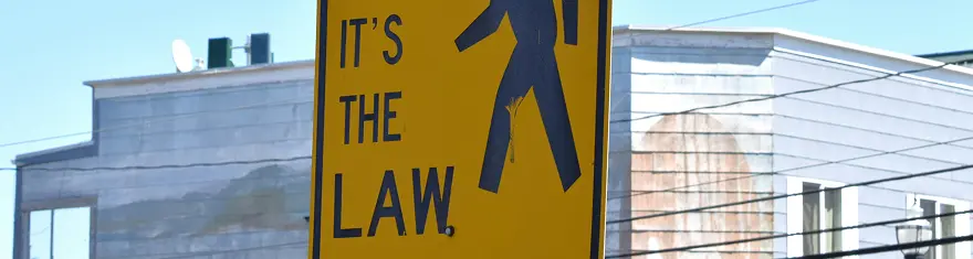 Yellow road sign with the words IT'S THE LAW