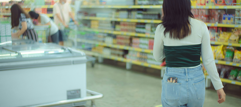 Back view of a brunette woman walking down a supermarket aisle