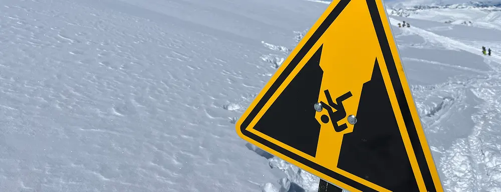Warning sign on snowy terrain indicating a pitfall or fall hazard
