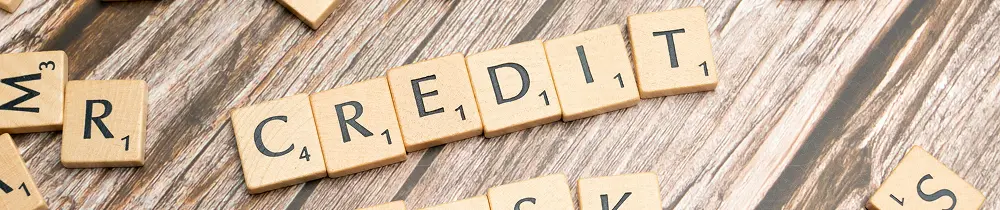 Scrabble tiles spelling CREDIT scattered on a wooden table