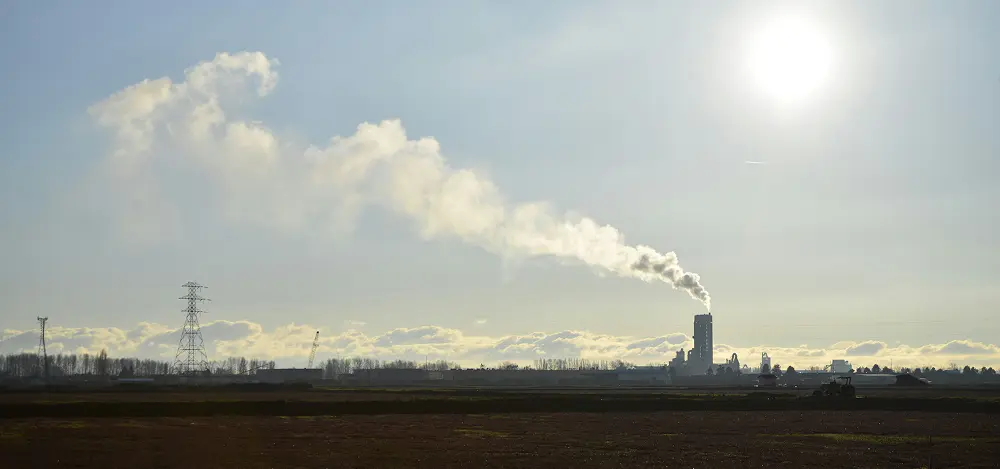 A sunny day over an industrial landscape with visible greenhouse gas emissions ghg rising into the sky