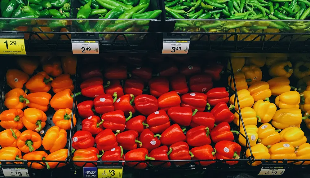 Close-up of colorful bell peppers displayed in a refrigerated grocery store section
