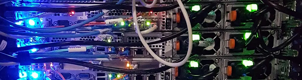 Close-up view of data center cables with black and blue wiring and glowing green indicator lights
