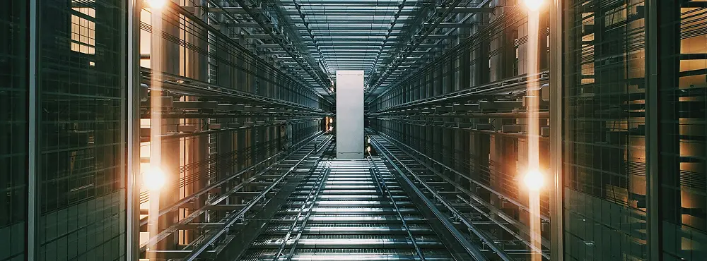 Interior view of a modern data center corridor with metal beams, glass walls, and glowing lights creating a symmetrical industrial design