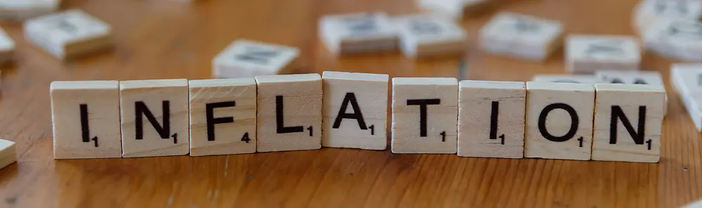 Scrabble tiles arranged on a wooden table spelling the word INFLATION