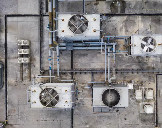 Aerial view of industrial rooftop with large cooling fans and connected piping