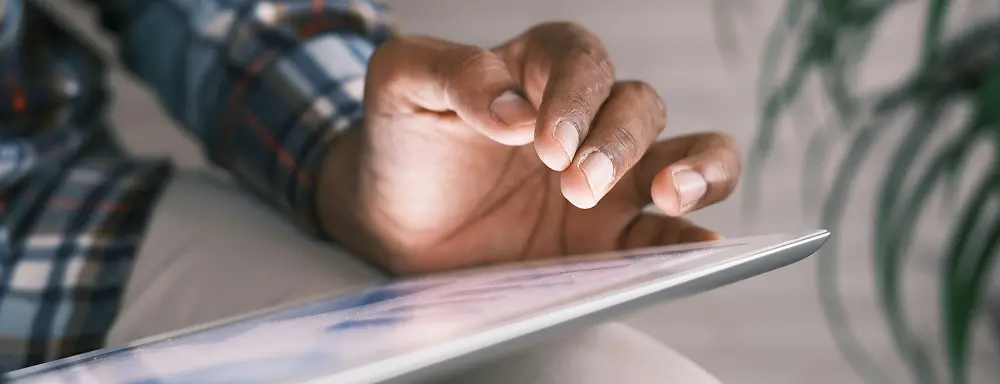 Male hand hovering above a tablet displaying a report