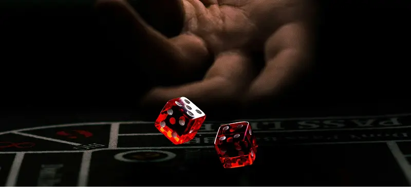 Two red translucent dice captured mid-roll across a felt casino gambling table