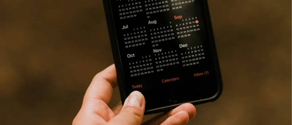 hand holding an iPhone with the calendar app open