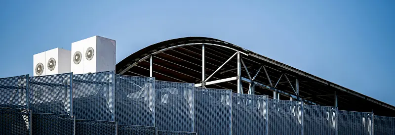 A light commercial HVAC unit installed on a covered building rooftop under a clear blue sky
