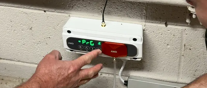 technician calibrating the AKO Refrigerant Leak Device, hand on the device