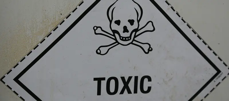 A close-up of a white diamond-shaped warning sign featuring a skull and crossbones and the word TOXIC