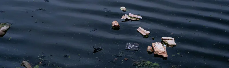 Plastic debris and trash floating on the surface of dark rippling water